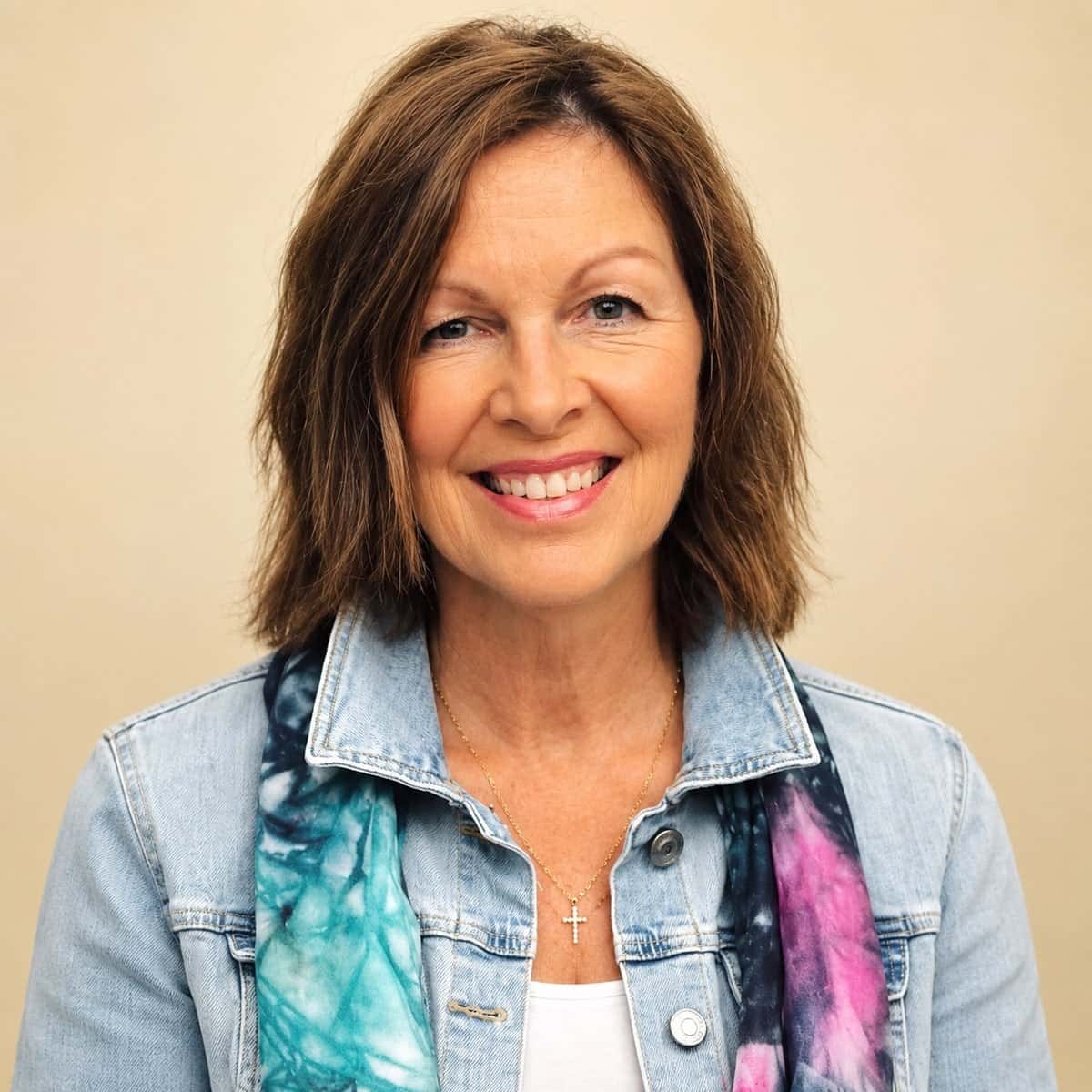 Barbie Hunt, smiling, in a denim jacket with a hand-dyed teal and pink silk scarf